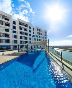 una piscina frente a un gran edificio en Beachfront 2BHK apartment at Al Mouj, en Seeb