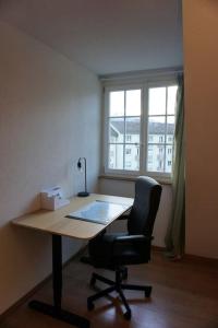 a desk in an office with a chair and a window at Stadt nah, Modern, bequem, in Thun