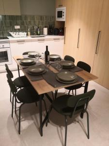 a wooden table with plates and wine glasses on it in a kitchen at Apartamento céntrico Sitges, cerca de todo andando in Sitges