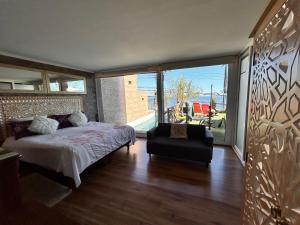 een slaapkamer met een bed en een stoel en een groot raam bij Pacificsunset Reñaca in Viña del Mar