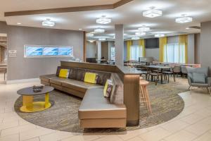 een hotellobby met een bank, tafels en stoelen bij SpringHill Suites Portland Airport in Portland