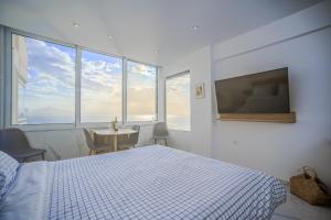 a bedroom with a bed and a tv and windows at Ble Property Atlas in Loutraki