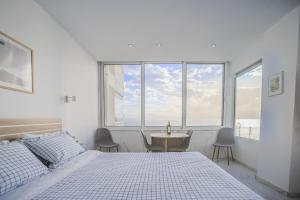 a white bedroom with a bed and a table and chairs at Ble Property Atlas in Loutraki