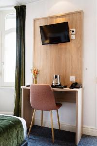 Zimmer mit einem Schreibtisch und einem TV an der Wand in der Unterkunft Hôtel Escurial - Centre Gare in Metz