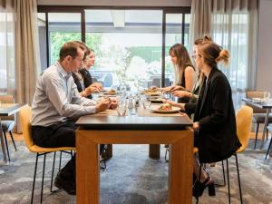 um grupo de pessoas sentadas em torno de uma mesa em um restaurante em Pullman Toulouse Airport em Blagnac