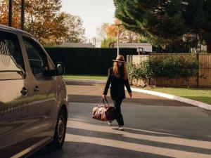 uma mulher andando pela rua com uma mala em Pullman Toulouse Airport em Blagnac