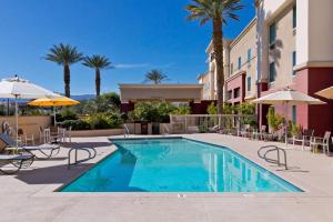 Hampton Inn & Suites Palm Desert في بالم ديزرت: وجود مسبح في الفندق مع الكراسي والمظلات