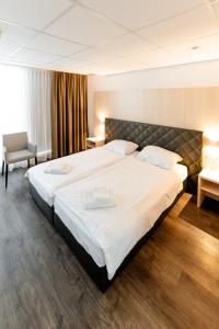 a hotel room with a large bed and a chair at Los Lorentes Apartments Bern Airport in Belp