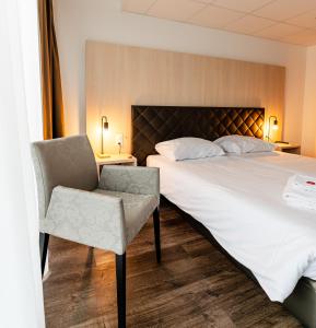 a hotel room with a bed and a chair at Los Lorentes Apartments Bern Airport in Belp