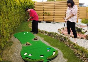 dos personas jugando golf en un campo de golf artificial en Hananoyado Yumefuji, en Fujikawaguchiko