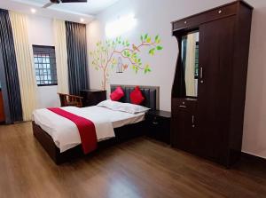 a bedroom with a bed and a tree mural on the wall at Ayurguru Ayurvedic Kalari Resort in Sultan Bathery