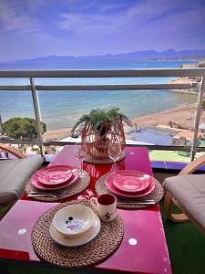 - une table avec des assiettes et des tasses roses et une vue sur la plage dans l'établissement Blue Salou, à Salou