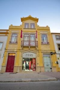 um edifício amarelo com portas e janelas vermelhas em O Paço - exclusive accommodation em Tomar