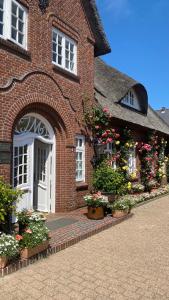 un edificio de ladrillo con una puerta blanca y flores en Hotel und Restaurant Jörg Müller, en Westerland