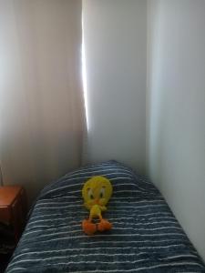 um urso de peluche amarelo sentado em cima de uma cama em Cabañas La Herradura em Coquimbo