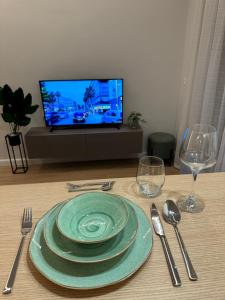 une table avec une plaque et des ustensiles de cuisine ainsi qu'une télévision dans l'établissement Nomad Stay Apartments, à Durrës