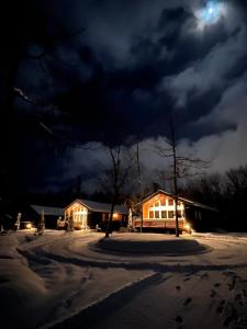 una casa nella neve di notte con la luna di Chill Village a Biei