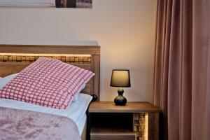 a bed with a pink pillow and a lamp on a table at Apartament Orlando w Porto Łeba 350m od morza in Łeba