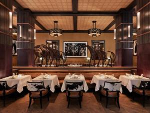 una sala da pranzo con tavoli, sedie e lampadari a braccio di Bowie House, Auberge Resorts Collection a Fort Worth