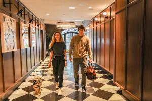 een man en vrouw die door een gang lopen met hun honden bij Hotel Belleclaire Central Park in New York