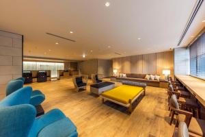 uma sala de estar com cadeiras azuis e uma mesa amarela em Via Inn Prime Sapporo Odori em Sapporo