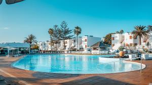 a swimming pool at a resort with palm trees and buildings at Labranda Bahía de Lobos in Corralejo