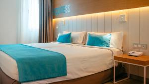 a hotel room with a large bed with blue pillows at Labranda Bahía de Lobos in Corralejo