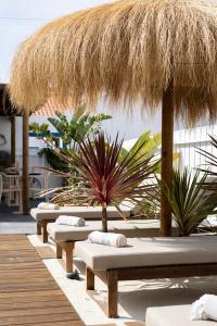 a row of lounge chairs with a straw umbrella at Casa Idalia Boutique Hotel in Comporta