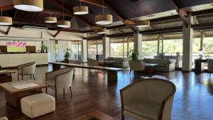 un grand hall avec des chaises, des tables et des fenêtres dans l'établissement Hotel Raices Esturion, à Puerto Iguazú