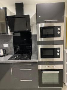 een keuken met een kookplaat, een oven en een magnetron bij Résidence Amaya - haut standing au bord de l'Oise in Pontoise