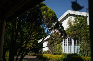 Una casa blanca con un árbol delante. en Marlihill Bungalow - a CGH Earth SAHA Experience, en Ooty