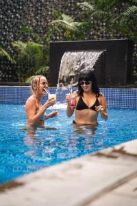 duas mulheres numa piscina com bebidas em The Acacia Hotel & Spa em Candolim