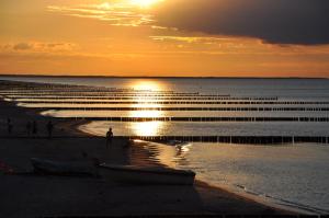 einen Strand bei Sonnenuntergang mit einem Boot an der Küste in der Unterkunft SEETELHOTEL Nautic Usedom Hotel & Spa in Ostseebad Koserow