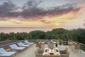 uma vista do deque de um resort com cadeiras e mesas em The Acacia Hotel & Spa em Candolim