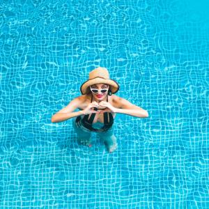 uma mulher de chapéu de palha numa piscina em The Acacia Hotel & Spa em Candolim