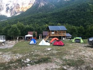 un grupo de tiendas sentadas en un campo frente a una montaña en Bujtina Diti, en Tropojë