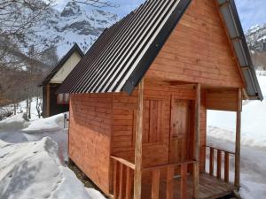 Cabaña de madera con techo de metal en la nieve en Bujtina Diti, en Tropojë