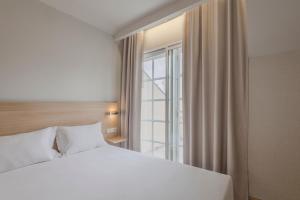 een slaapkamer met een wit bed en een raam bij Moov Hotel Porto Centro in Porto