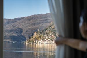 una mujer mirando por una ventana en un castillo en una colina en Villa Patria B&B, en Brusino Arsizio