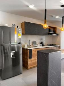 a kitchen with a stainless steel refrigerator and wooden cabinets at Lujoso apartamento central, nuevo y cómodo in Pereira