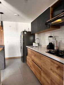 a kitchen with a stainless steel refrigerator and wooden cabinets at Lujoso apartamento central, nuevo y cómodo in Pereira