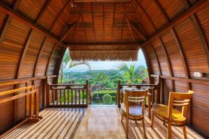 um quarto com uma varanda com uma mesa e cadeiras em Sebuluh Sunset Hill em Nusa Penida