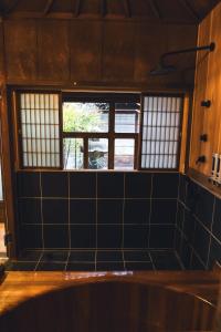 Habitación con 3 ventanas y pared de azulejos. en Johns House じょんのやど, en Himeji