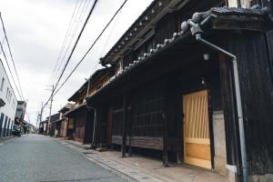 una calle vacía en una ciudad asiática con edificios en Johns House じょんのやど, en Himeji