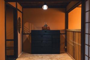 Vestidor negro en una habitación con una pared naranja en Johns House じょんのやど, en Himeji