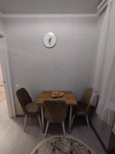 einen Esstisch mit Stühlen und eine Uhr an der Wand in der Unterkunft Balti Apartment in Bălţi