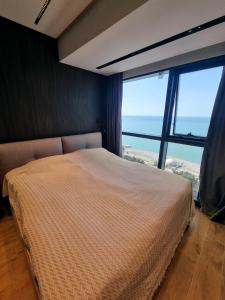 ein Schlafzimmer mit einem Bett und einem großen Fenster in der Unterkunft Premium apartment in Porta Batumi Tower in Batumi