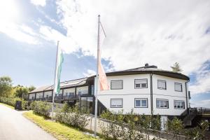 a white building with flags on the side of a road at zum Sausaler - Boutique Hotel-Pension Südsteiermark in Sankt Nikolai im Sausal