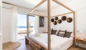 a bedroom with a canopy bed with a view of the ocean at Victoria Sunset Suites in San Antonio