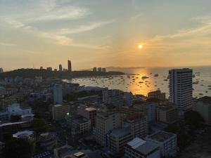 Edge Central Pattaya by Thida في باتايا سنترال: أفق المدينة مع غروب الشمس على المياه